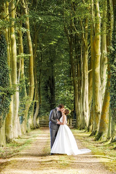 bride-groom-kissing-tree-lined-avenue